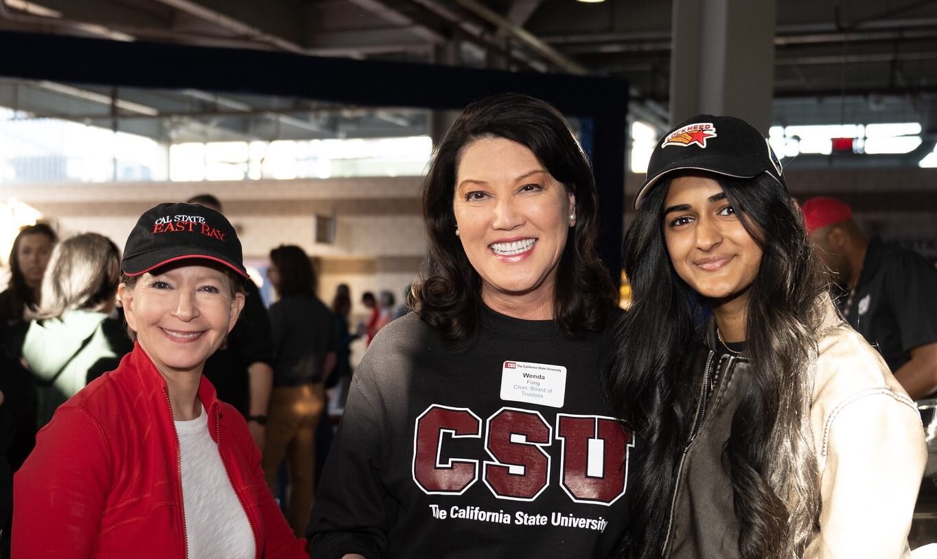 three smiling women at a baseball game