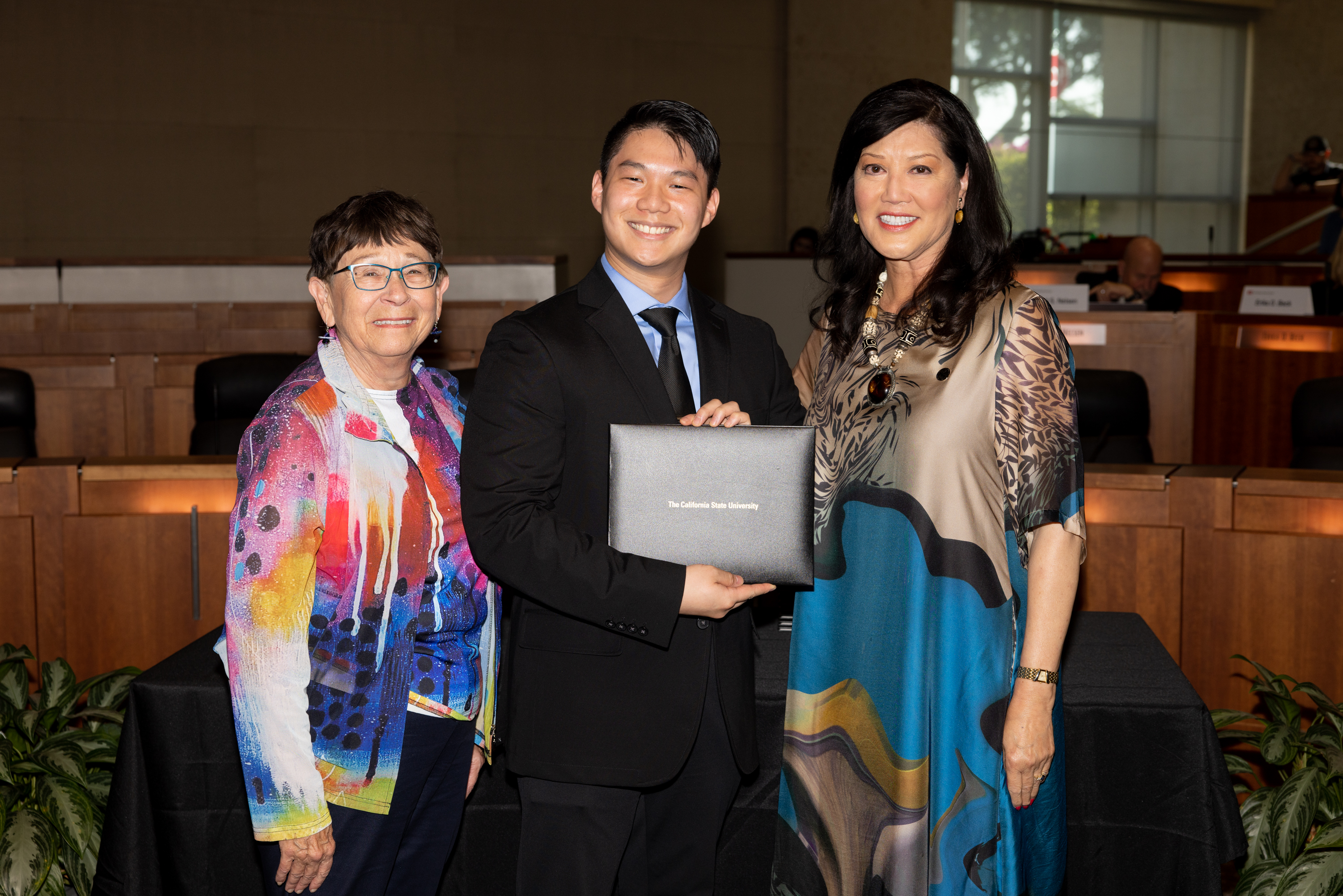 two women presenting a college student with an award