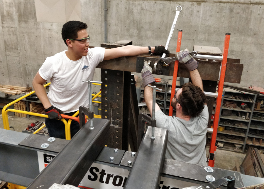 Graduate students Jerry Luong and Rory de Sevilla install a custom built bracket that will support a hydraulic jack and be used to simulate earthquake forces on a full-scale concrete wall as part of their masters research under Professor Michael Deigert.