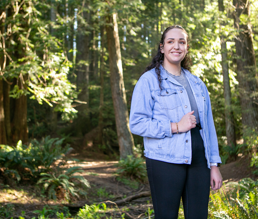 Maria poses amongst trees.