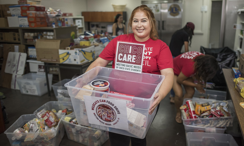Chico State studetn posing with plastic bin full of donated food