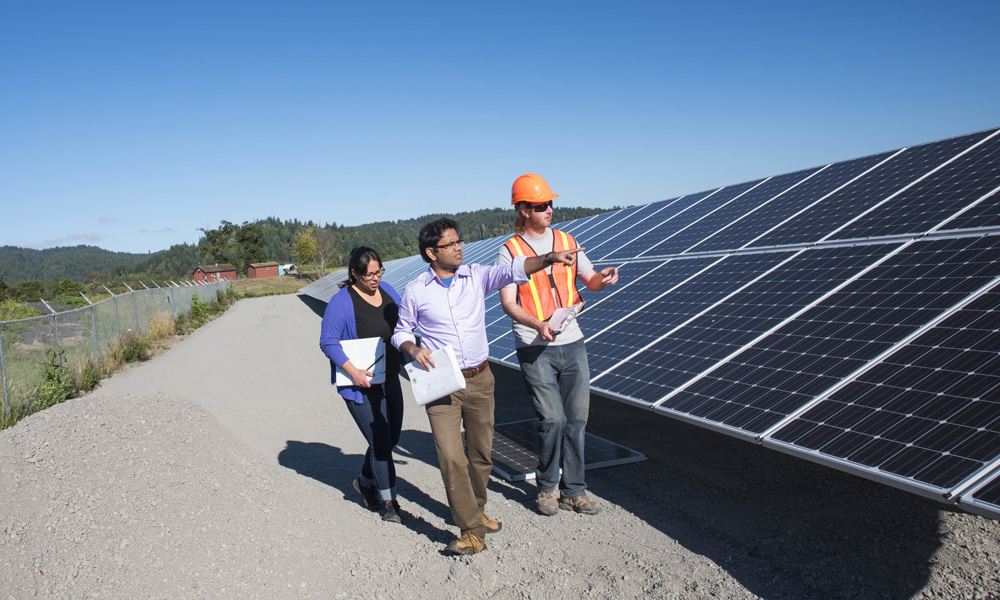 students walk alongside large solar panels