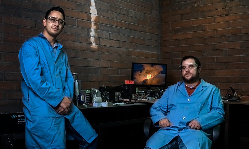 two men in lab coats smiling for camera in a lab setting